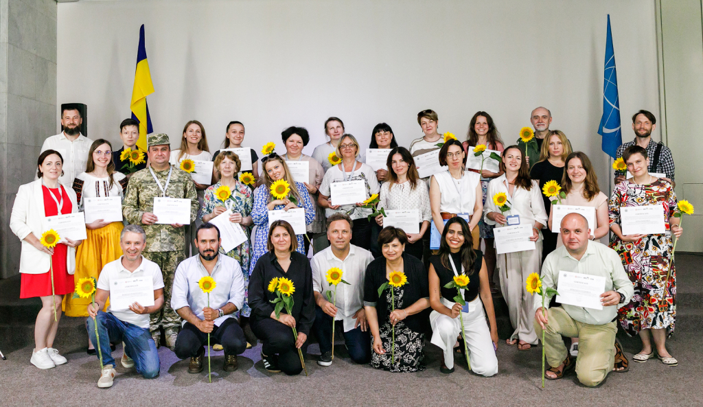 Les participants tiennent leurs certificats et un tournesol, symbole de la paix et de la résilience en Ukraine Crédit : Maidan Museum/ICCROM – Bohdan Poshyvailo