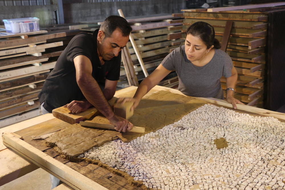 Trainees applying temporary clay backing to allow a mosaic to be safely turned over and its facing removed